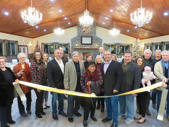 Cathy Daboul of River Valley Family Medical handles the scissors at the Greater Barryville Chamber of Commerce's January 7, 2019 ribbon-cutting celebrating the newly opened 200-seat banquet room at the Catskill Mountains Resort. Resort owner William Zaccari is at her left.